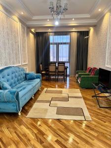 uma sala de estar com um sofá azul e uma mesa em London House Apartment em Baku