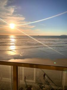a view of the beach at sunset from a balcony at Beautiful Beach Front Condo near Downtown in Rosarito
