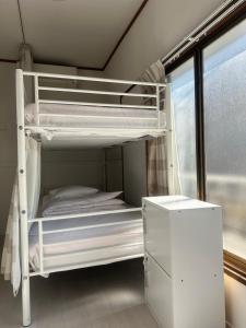ein weißes Etagenbett in einem Zimmer mit Fenster in der Unterkunft Keys House in Tokio