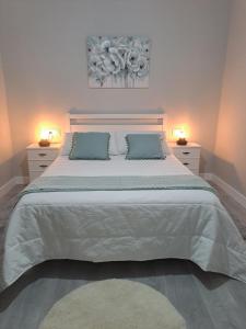 1 dormitorio con 1 cama blanca grande y 2 lámparas en Casa Arieira, en Cangas de Morrazo