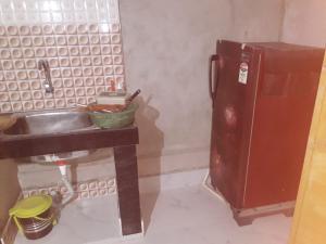 a kitchen with a sink and a rusty refrigerator at Sudha Kutir Puri in Puri