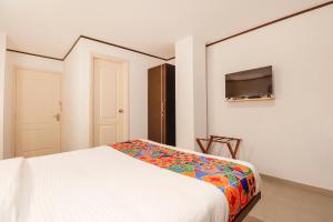 a bedroom with a bed and a flat screen tv at FabHotel Park Inn Indiranagar in Bangalore