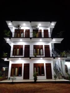Un grand bâtiment blanc avec balcon est disponible la nuit. dans l'établissement Saimon Villa, à Mirissa