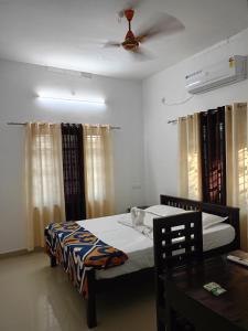 a bedroom with two beds and a ceiling fan at Enna homestay in Varkala
