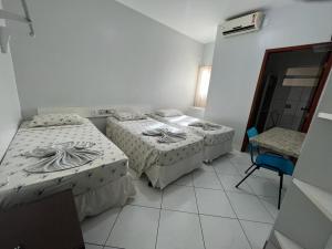 a room with three beds and a chair in it at Hotel Praia Corais de Maceió Novo in Maceió