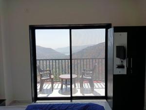 a room with a balcony with a table and chairs at Western Valley Cottages , Panchagani in Panchgani