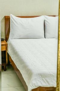 a bed with white sheets and pillows and a table at THANH NGỌC HOTEL in Ho Chi Minh City