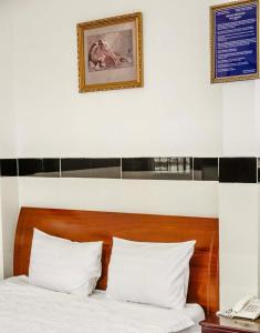 a bed with white pillows and a picture on the wall at THANH NGỌC HOTEL in Ho Chi Minh City