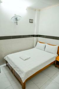 a bed with white sheets and a light on the wall at THANH NGỌC HOTEL in Ho Chi Minh City