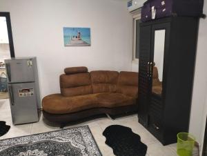 a living room with a brown couch and a refrigerator at ZED Hostel (Mix Share Studio) in Abu Dhabi
