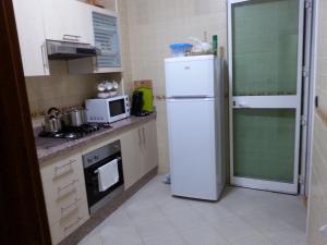 cocina con nevera blanca y microondas en Apartment Residence Rivaldi, en Mediouna
