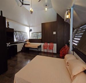 1 dormitorio con 1 cama y 2 sillas rojas en Sandy's Farm Stay, en Coimbatore