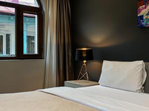 ein Schlafzimmer mit einem Bett mit einer Lampe neben einem Fenster in der Unterkunft Silver 39 Corner Hotel in Tbilisi City