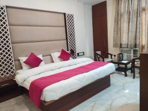 a bedroom with a large bed with red and white pillows at Hotel Indo Continental in New Delhi