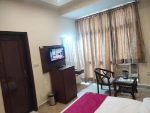 ein Hotelzimmer mit einem Bett, einem TV und einem Stuhl in der Unterkunft Hotel Indo Continental in Neu-Delhi