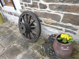 a wooden wagon wheel next to a pot with yellow flowers at LA FOLLE PARENTHESE in Vireux-Molhain