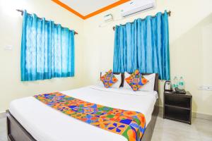 a bedroom with two beds and blue curtains at FabExpress Shanel Beachside Resort in Baga