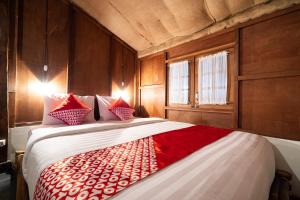 馬格朗的住宿－OYO 2393 Putroyono Homestay，一间卧室配有一张带红色和白色枕头的大床