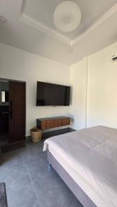 a bedroom with a bed and a flat screen tv at Airanda Phuket Homestay in Ban Suan