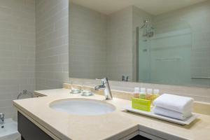 bagno con lavandino e specchio di Le Méridien City Center Doha a Doha