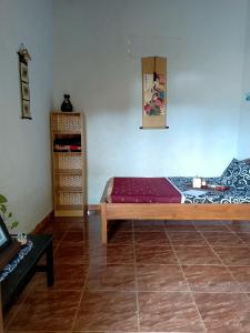 1 dormitorio con cama de madera y suelo de baldosa en IjenBromo Hub Omyah Isun Hub, en Ketapang