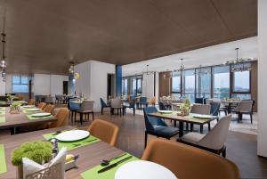 un restaurante con mesas, sillas y ventanas en Hampton by Hilton Guangzhou Luoxi en Cantón