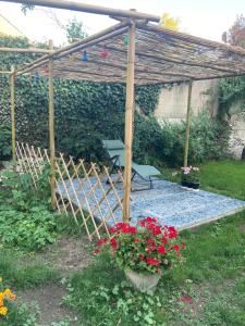 a wooden pergola with a picnic table and flowers at Coup de cœur en Brenne in Martizay