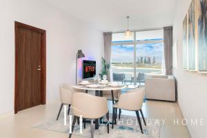 ein Esszimmer mit einem Tisch, Stühlen und einem Fenster in der Unterkunft LUX - Opulent Island Suite 3 in Dubai