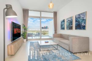 ein Wohnzimmer mit einem Sofa und einem TV in der Unterkunft LUX - Opulent Island Suite 3 in Dubai