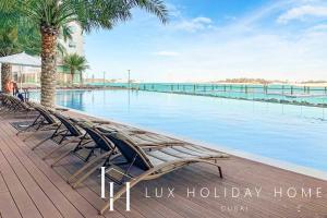 eine Reihe von Stühlen neben einem Pool in der Unterkunft LUX - Opulent Island Suite 3 in Dubai