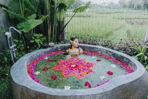 una mujer en un estanque de flores en un jardín en Tri Dewi Residence by Pramana Villas en Ubud