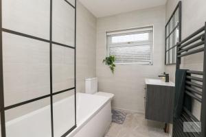 La salle de bains blanche est pourvue d'une baignoire et d'un lavabo. dans l'établissement Newly Renovated 3 Bedroom House with Parking by Amazing Spaces Relocations Ltd, à Liverpool
