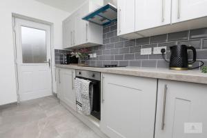 a kitchen with white cabinets and a stove top oven at Newly Renovated 3 Bedroom House with Parking by Amazing Spaces Relocations Ltd in Liverpool