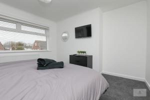 a white bedroom with a bed and a flat screen tv at Newly Renovated 3 Bedroom House with Parking by Amazing Spaces Relocations Ltd in Liverpool