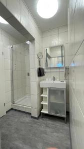 uma casa de banho branca com um lavatório e um chuveiro em Appartement Pension Schüßler em Waldeck