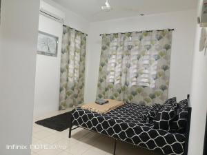 a bedroom with a bed with a black and white comforter at Homestay Izzauni in Kuantan
