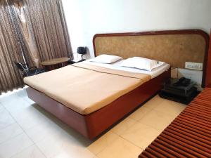 a bedroom with a large bed with a wooden headboard at Hotel Diana Gandhipuram in Coimbatore