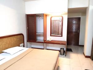 a bedroom with a bed and a window and a table at Hotel Diana Gandhipuram in Coimbatore