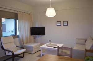 a living room with a couch and a table and a tv at Caravel Apartments Stalis in Stalida