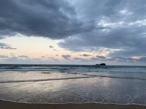 a beach with a cloudy sky and the ocean at Little Whale House in Mudjimba