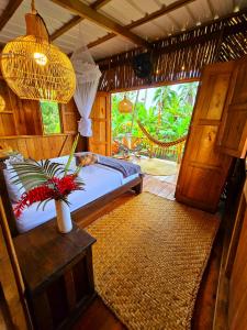 ein Schlafzimmer mit einem Bett und einer Vase mit Blumen auf dem Tisch in der Unterkunft TORTUGA BAY Eco Hotel in El Valle