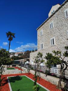 a large stone building with a green yard at Apartments Harriet in Dubrovnik