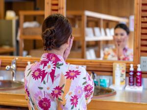 a woman looking at her reflection in a mirror at Kusatsu-onsen Hotel Resort in Kusatsu
