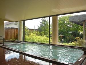 a swimming pool in a building with a large window at Kusatsu-onsen Hotel Resort in Kusatsu