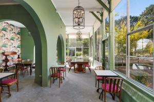 um restaurante com mesas, cadeiras e janelas em Victoria and Albert Guesthouse em Mount Victoria