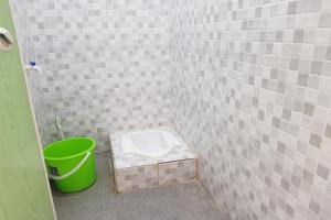 a bathroom with a toilet and a green bucket at OYO 93771 Sejolie Sibayak in Berastagi