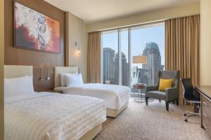 a hotel room with two beds and a desk and a window at Le Méridien City Center Doha in Doha