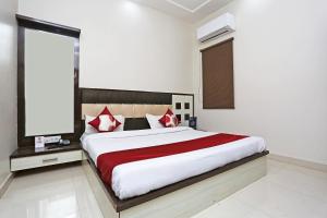 a bedroom with a large bed with red and white pillows at OYO KN Plaza in Sikandra
