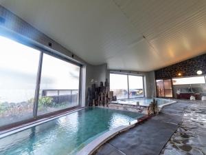 a large swimming pool in a building with windows at Kusatsu-onsen Hotel Resort in Kusatsu