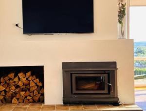 a fireplace with a pile of fire wood and a flat screen tv at The Tassie - Luxury with panoramic water views in Hobart